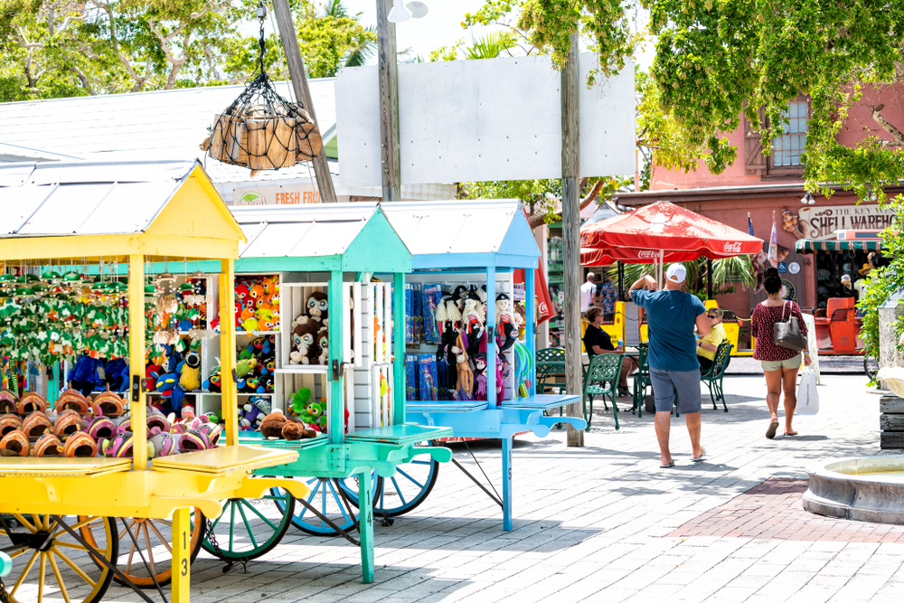 Key West, USA - May 1, 2018: Duval street Mallory Square outdoor shopping mall, market, people walking, buying souvenirs, in summer Florida city, multicolored stands, booth, kiosk selling toys