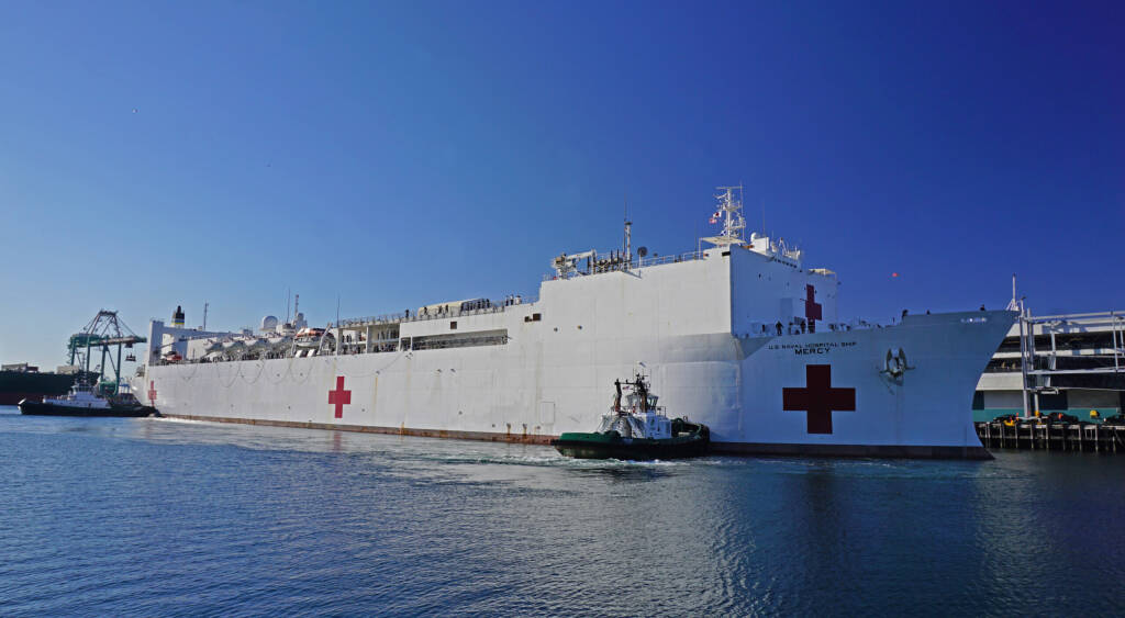 San Pedro, California USA - March 27, 2020: US Navy Hospital ship Mercy docks at the Port of Los Angeles harbor, assisted by tugboats, to provide medial assistance during Covid-19 coronavirus pandemic