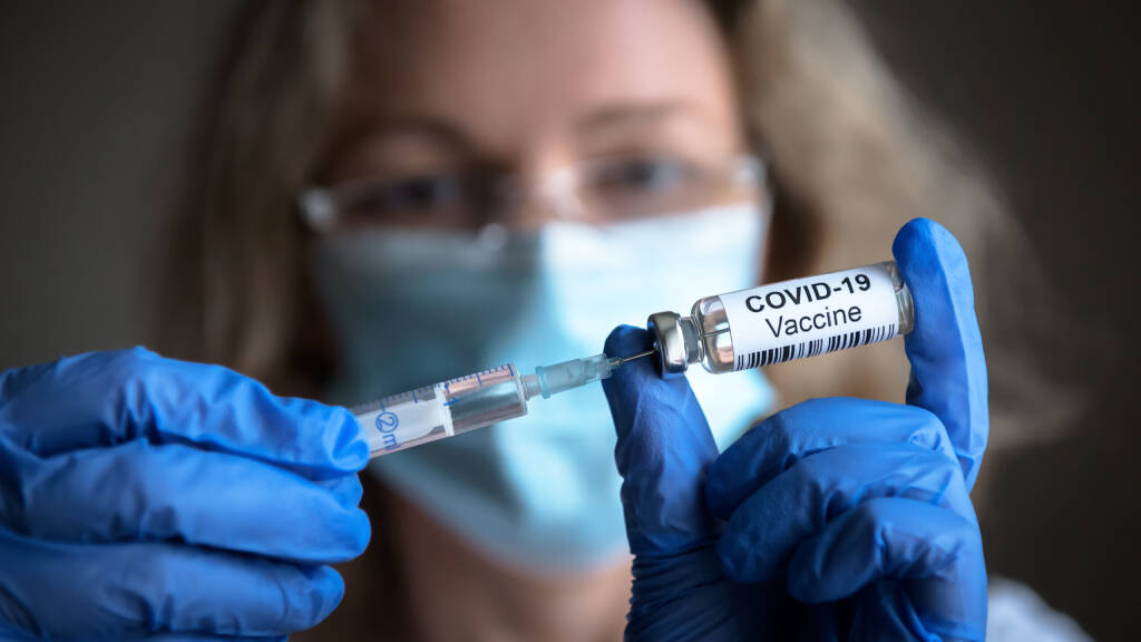 Szczepionka COVID-19 w rękach badaczy, lekarz trzyma strzykawkę i butelkę ze szczepionką do leczenia koronawirusem. Koncepcja leczenia wirusem korony, iniekcji, strzału i badania klinicznego podczas pandemii.