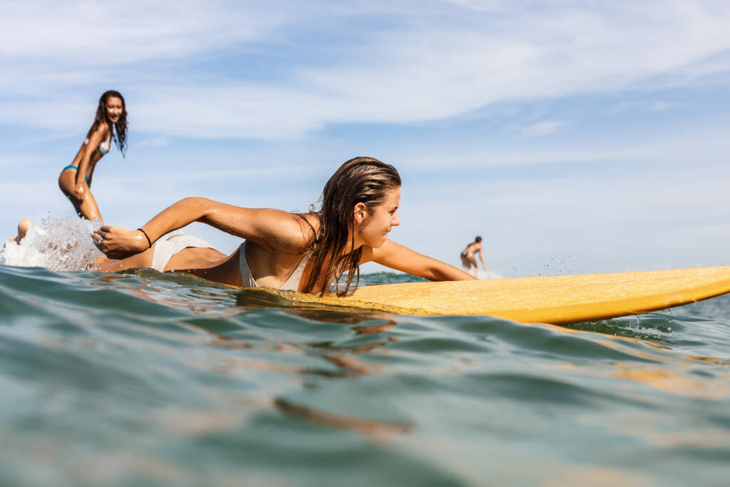 Dwie surfujące kobiety. Aktywny sport styl życia i letnie wakacje