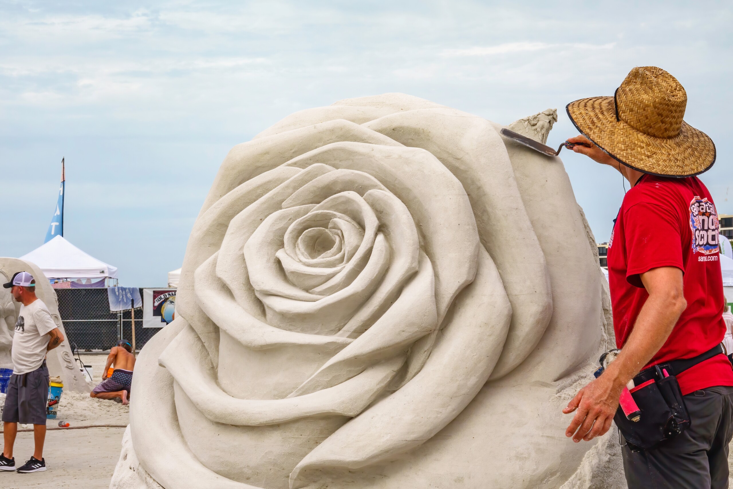SARASOTA, FLORYDA, USA — LISTOPAD 12 października 2021: Artysta wygładza część rzeźby kwiatowej w toku Siesta Key Crystal Classic, międzynarodowy festiwal rzeźbienia w piasku na plaży Siesta Key.