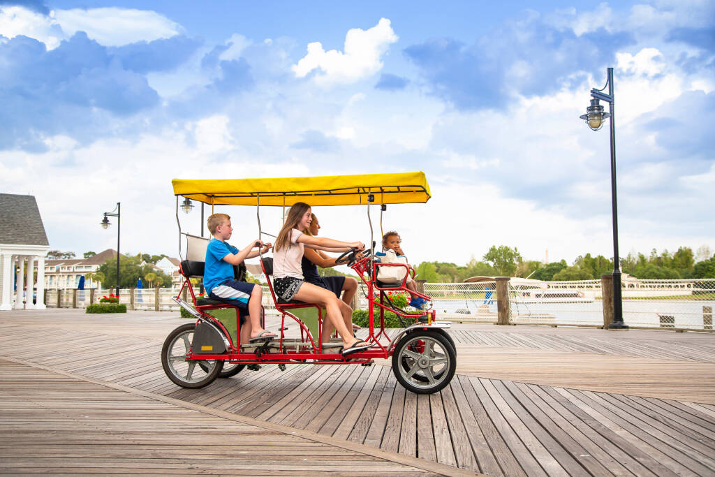 Młoda szczęśliwa rodzina jeżdżąca na rowerze tandemowym z podwójnym surrey na dużej promenadzie nad oceanem. Letnia zabawa na świeżym powietrzu z dziećmi, licencja: shutterstock/By Brocreative, licencja: shutterstock/By Brocreative