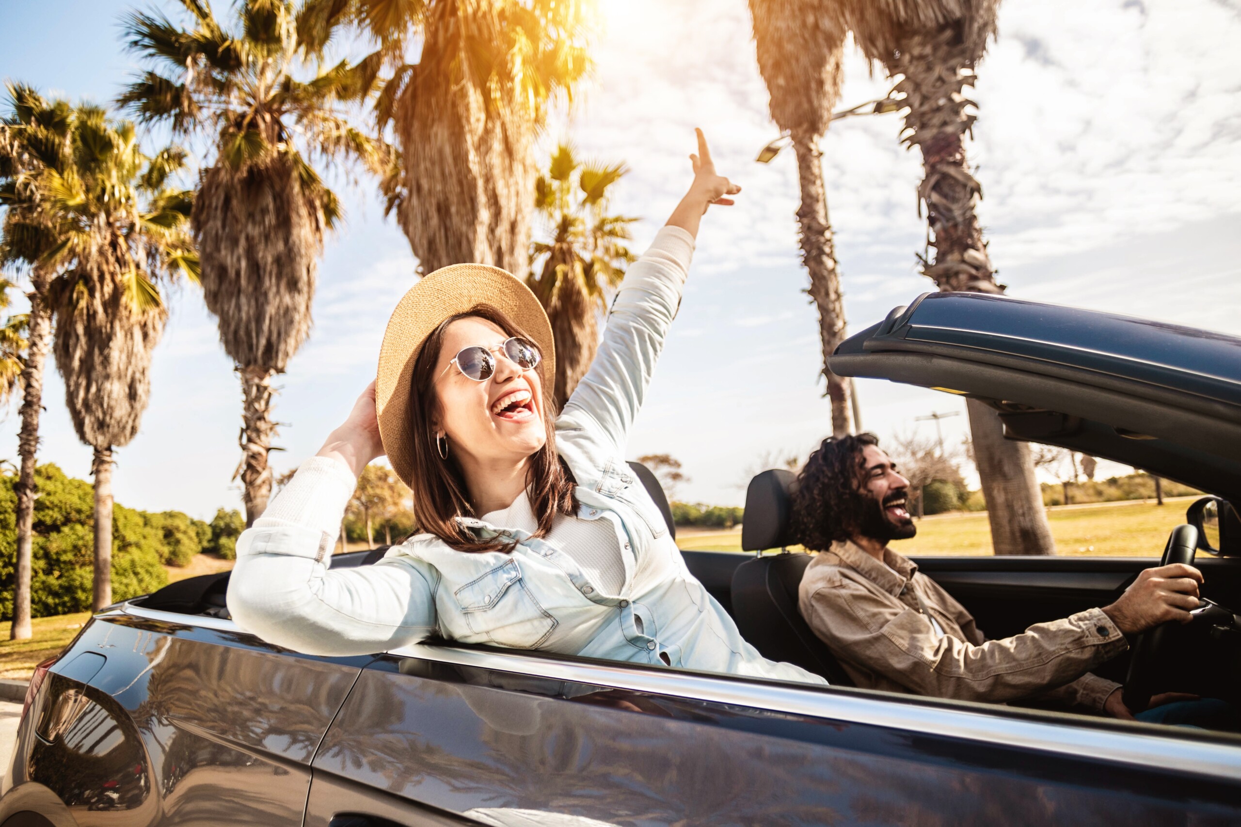 Szczęśliwa młoda para ciesząca się letnimi wakacjami na kabriolecie - mężczyzna i kobieta śmieją się podczas jazdy kabrioletem na zewnątrz., licencja: shutterstock/By Xavier+Lorenzo