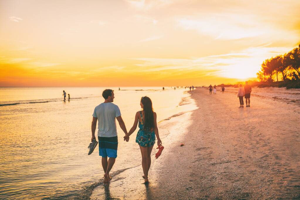 Plaża lato - szczęśliwa para korzystająca z zachódu słońca, spacer na plaży Shelling, Wyspa Sanibel, Floryda., licencja: shutterstock/By martinmark